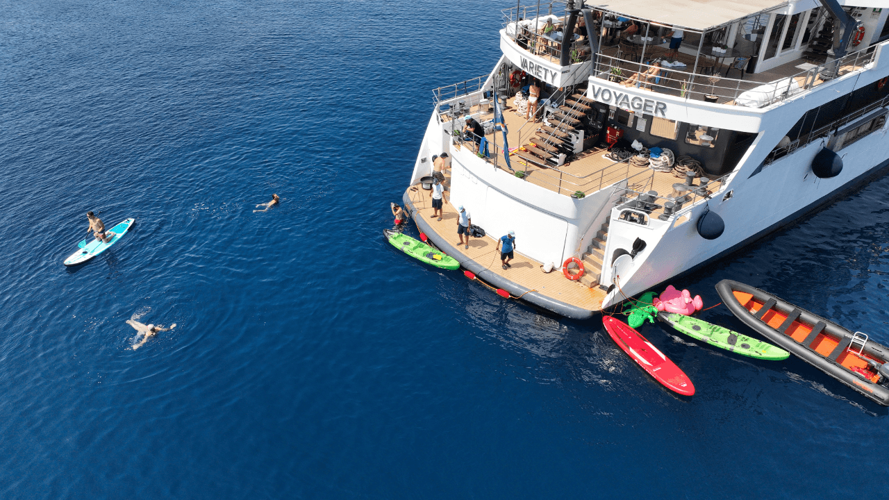 Water Sports Activities at Cruise Ship Passengers enjoy water sports activities including paddleboarding and swimming around a cruise vessel in crystal-clear Mediterranean waters.