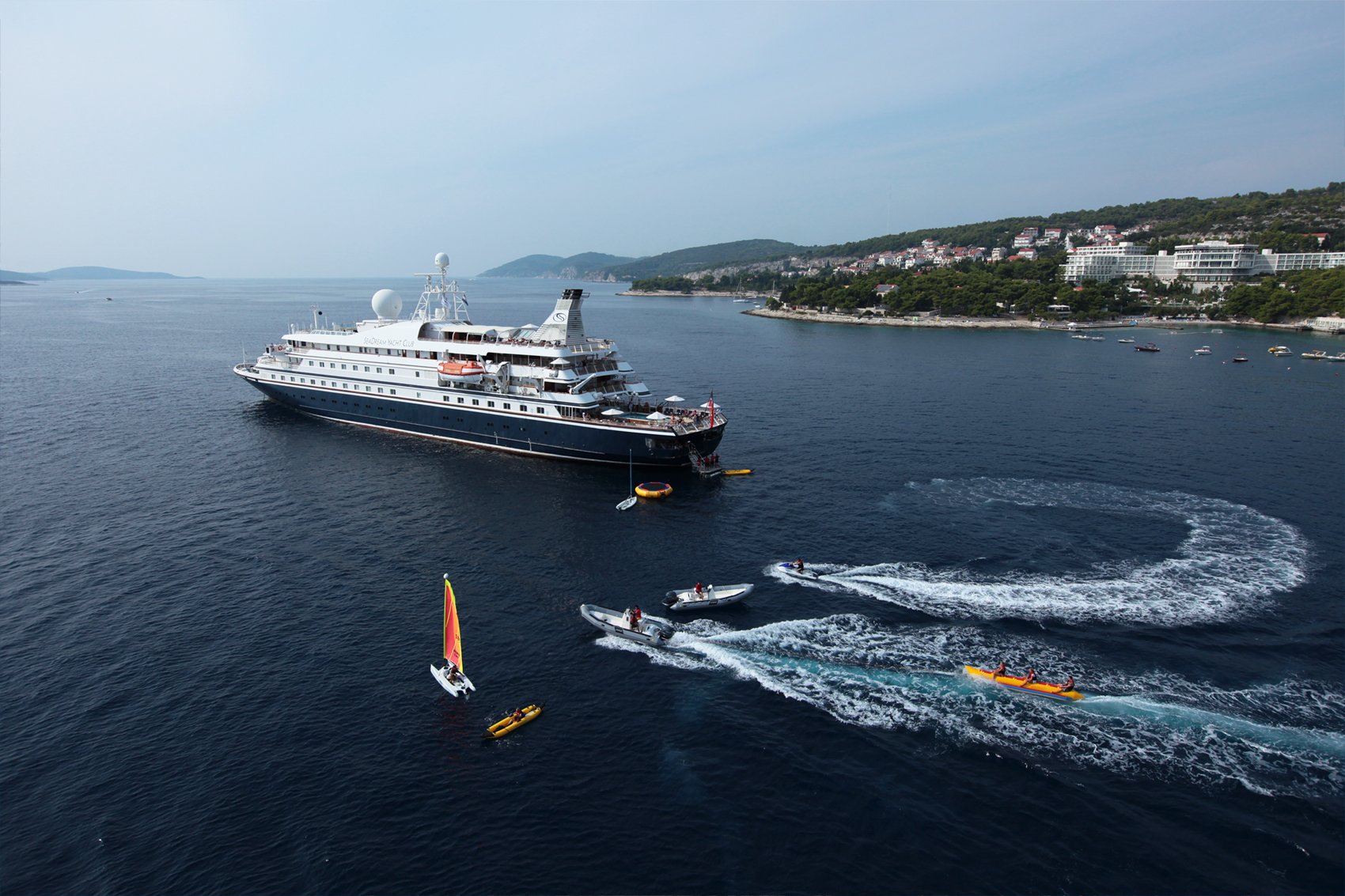 yachts_3 SeaDream yacht navigating through a dramatic fjord with steep green mountainsides
