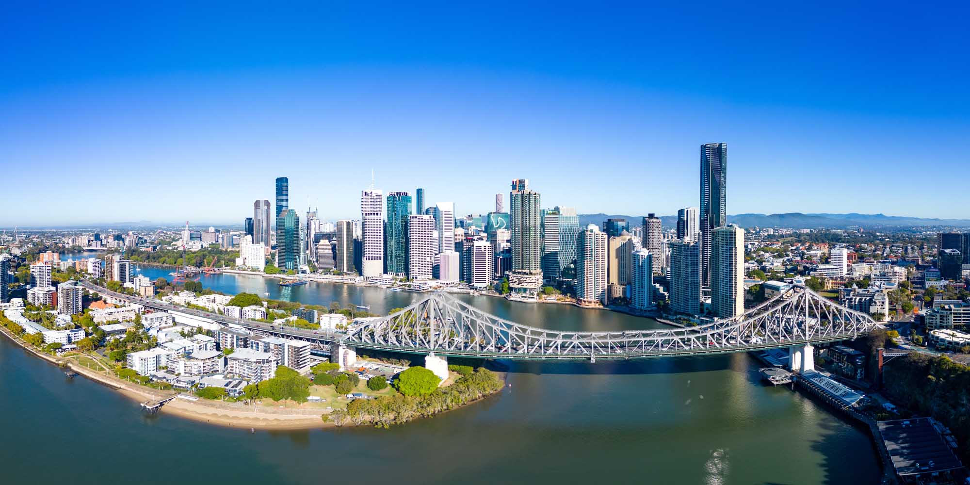 Tropical Beach Cove with Palm Trees An aerial photograph of Brisbane's downtown skyline featuring the iconic Story Bridge spanning the Brisbane River, with the city's modern skyscrapers reflected in the water.