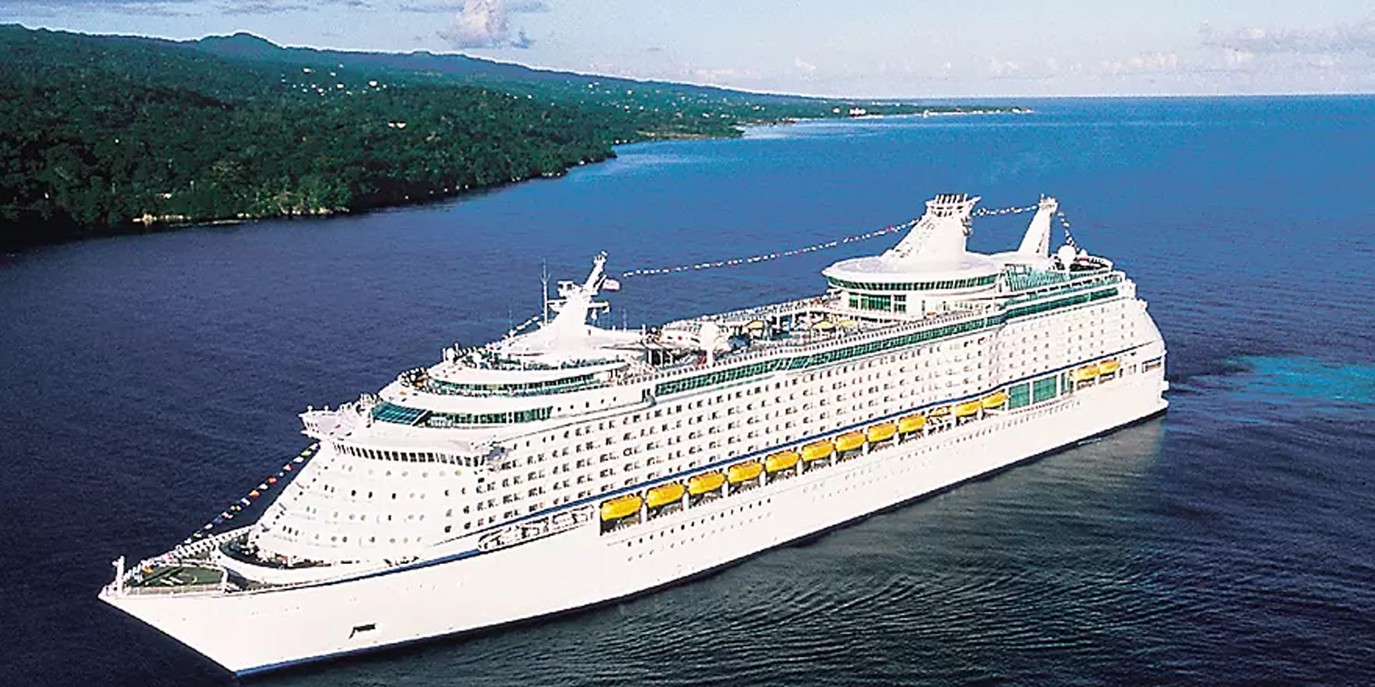 Large Cruise Ship Anchored in Tropical Waters A massive modern cruise ship with white hull and distinctive yellow lifeboats is anchored in clear