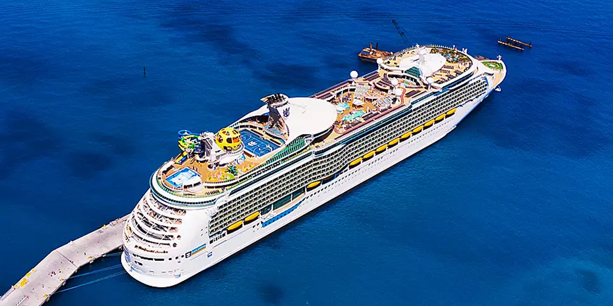 Large Cruise Ship Docked at Pier Aerial View An aerial photograph of a massive modern cruise ship docked at a pier, featuring multiple decks