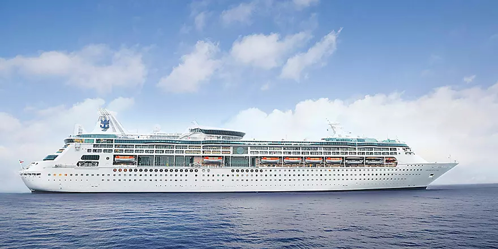 Large Cruise Ship at Sea A large white cruise ship with turquoise accents sails through calm blue waters under a partly