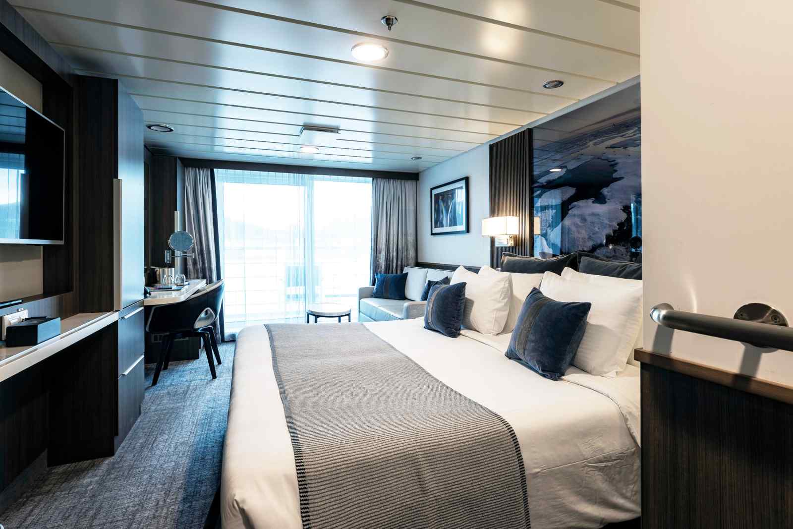 Luxury Cruise Ship Stateroom with Ocean View A contemporary luxury cruise ship stateroom featuring a king-size bed with white linens and blue