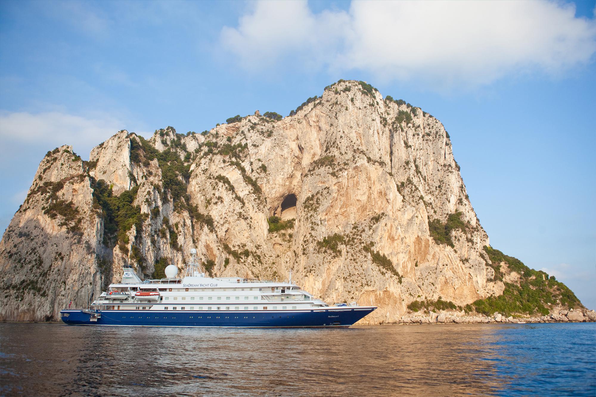 Luxury Cruise Ship at Capri’s Faraglioni Rocks Cruise ship anchored beneath dramatic limestone cliff formations in the Mediterranean