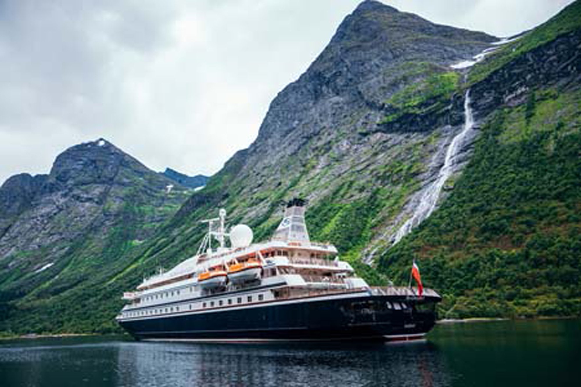 Luxury Cruise Ship in Norwegian Fjord A large expedition cruise ship anchors in a dramatic Norwegian fjord, surrounded by steep