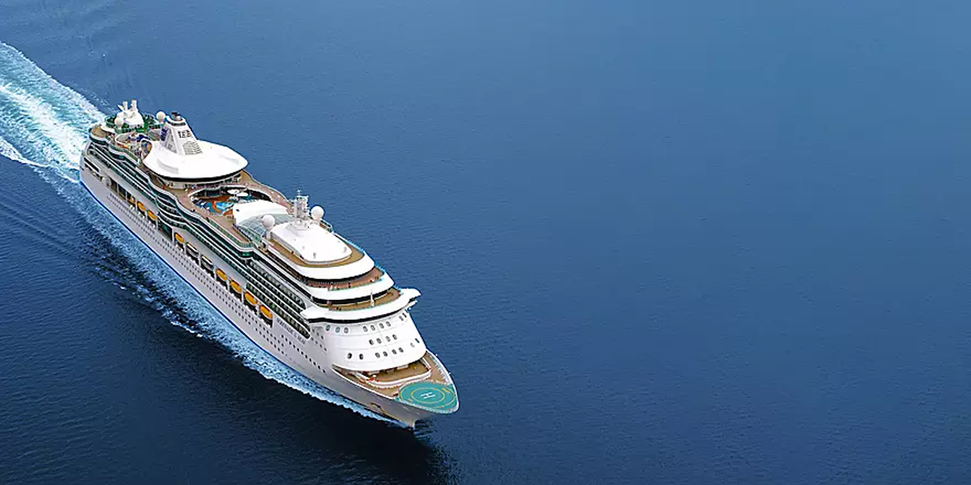 Luxury Cruise Ship in Open Ocean Waters An aerial view of a large modern cruise ship with multiple white decks and golden trim sailing