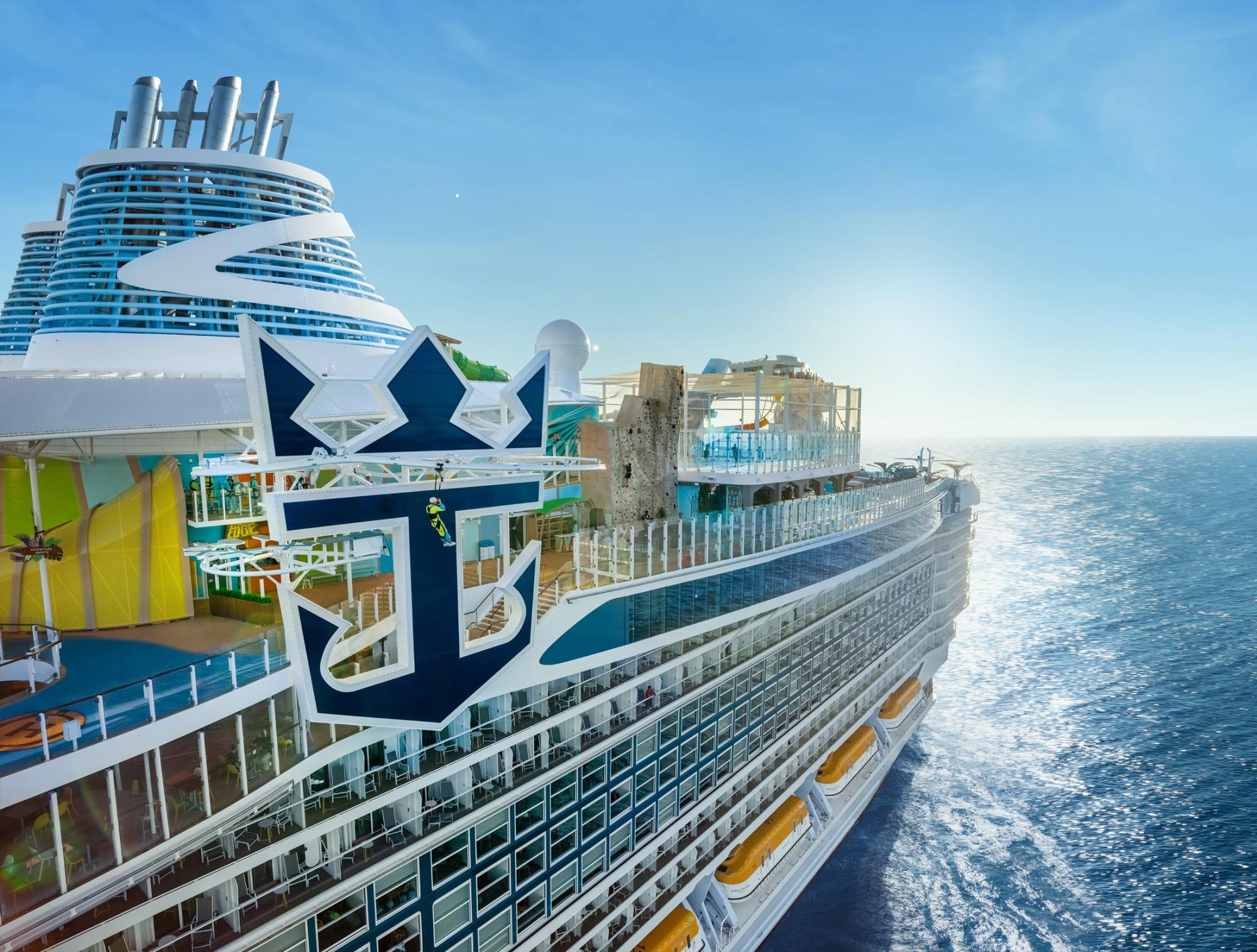 Modern Cruise Ship at Sea with Anchor Emblem A modern cruise ship with distinctive blue and white livery featuring a large anchor emblem on its hull, photographed from the side while at sea.