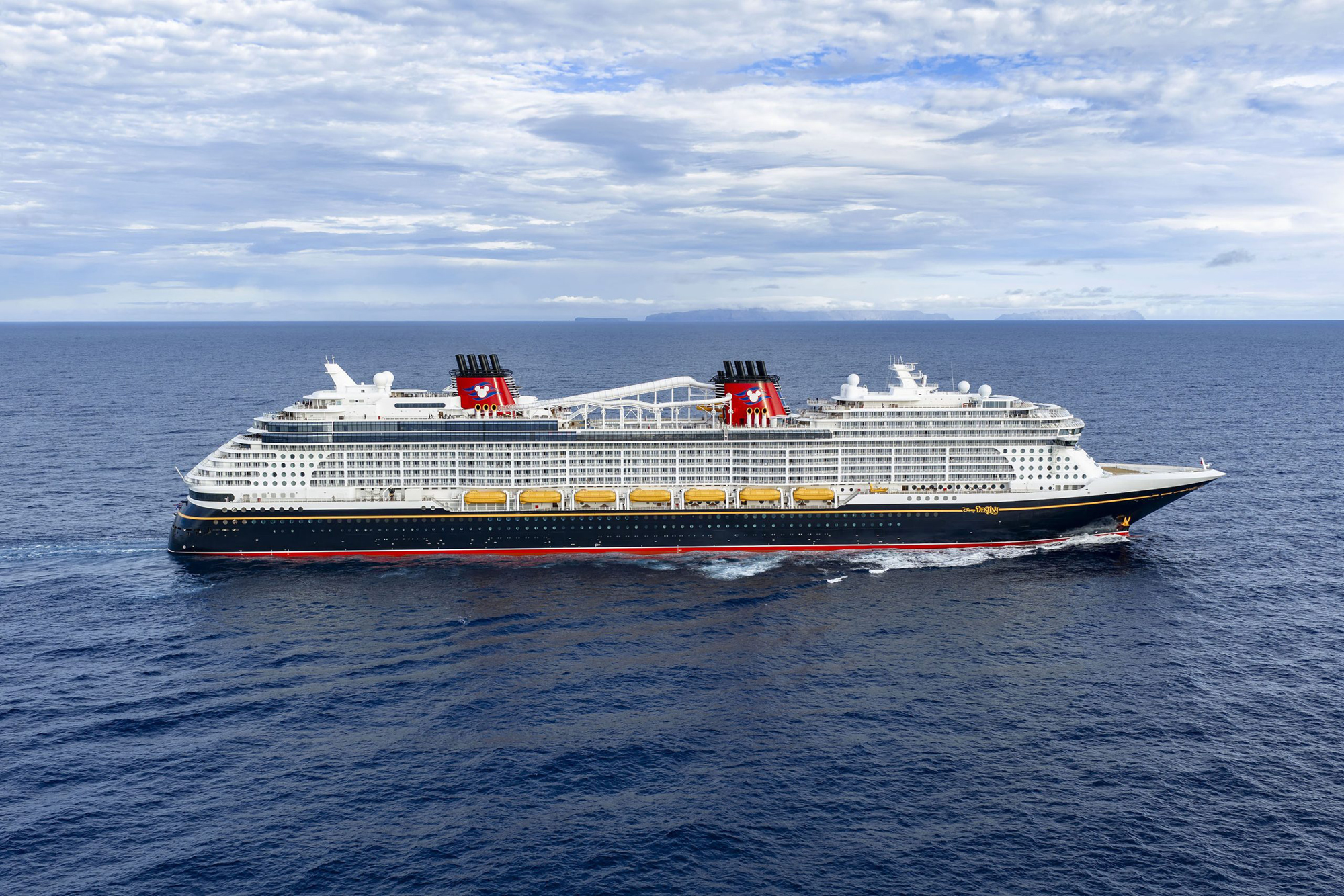 Modern Cruise Ship at Sea with Mountain Vista Disney cruise ship sailing through calm blue waters with mountains on the horizon