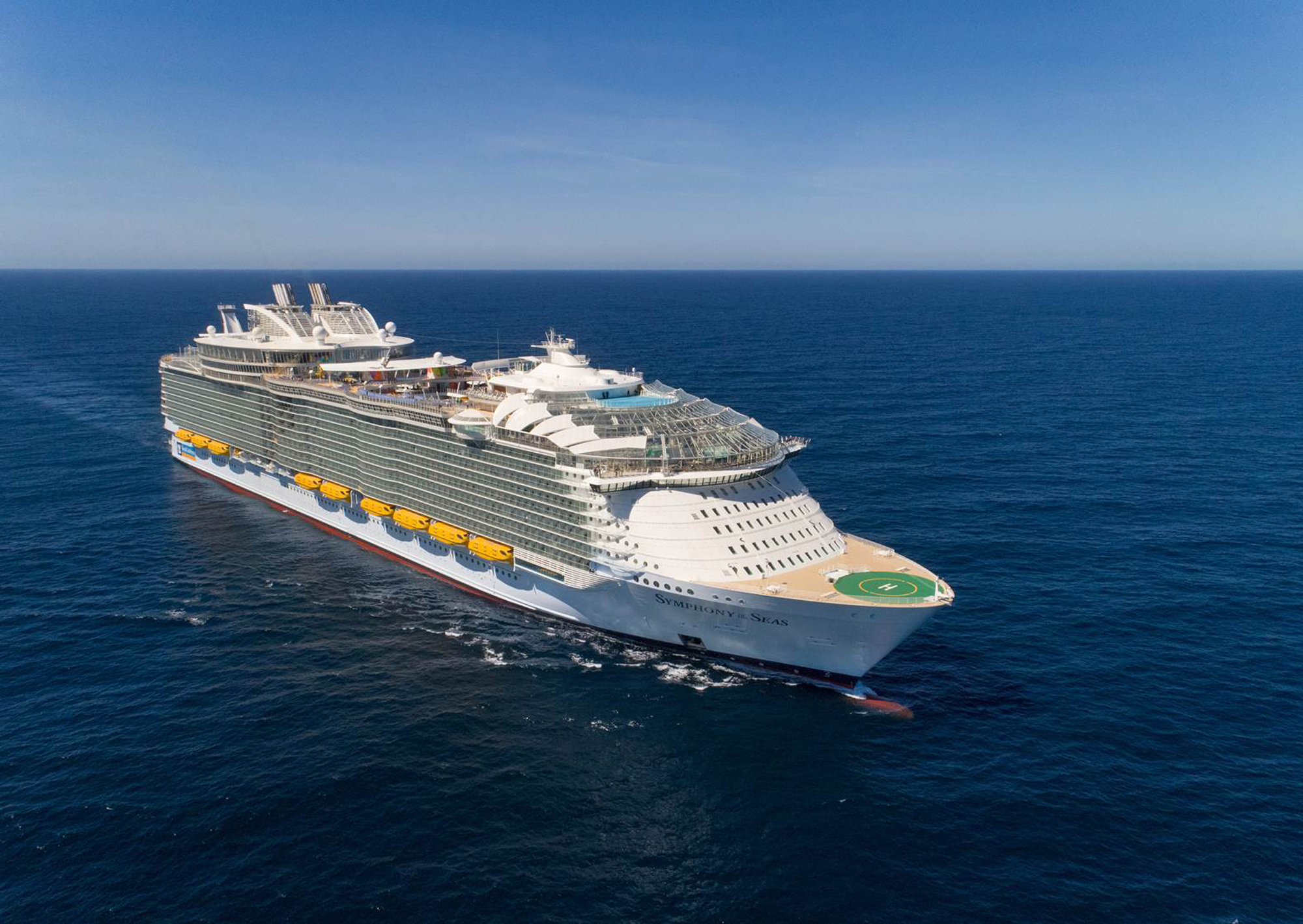 Modern Mega Cruise Ship on Open Ocean A massive modern cruise ship photographed from an aerial perspective, sailing on clear blue waters