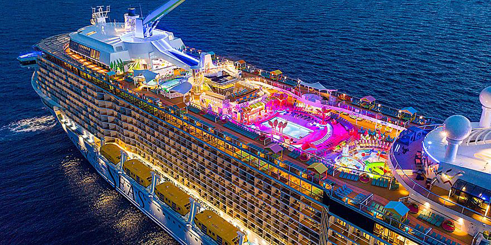 Odyssey of the Seas Night Pool Deck Aerial View An aerial nighttime photograph of a large modern cruise ship illuminated with vibrant colored