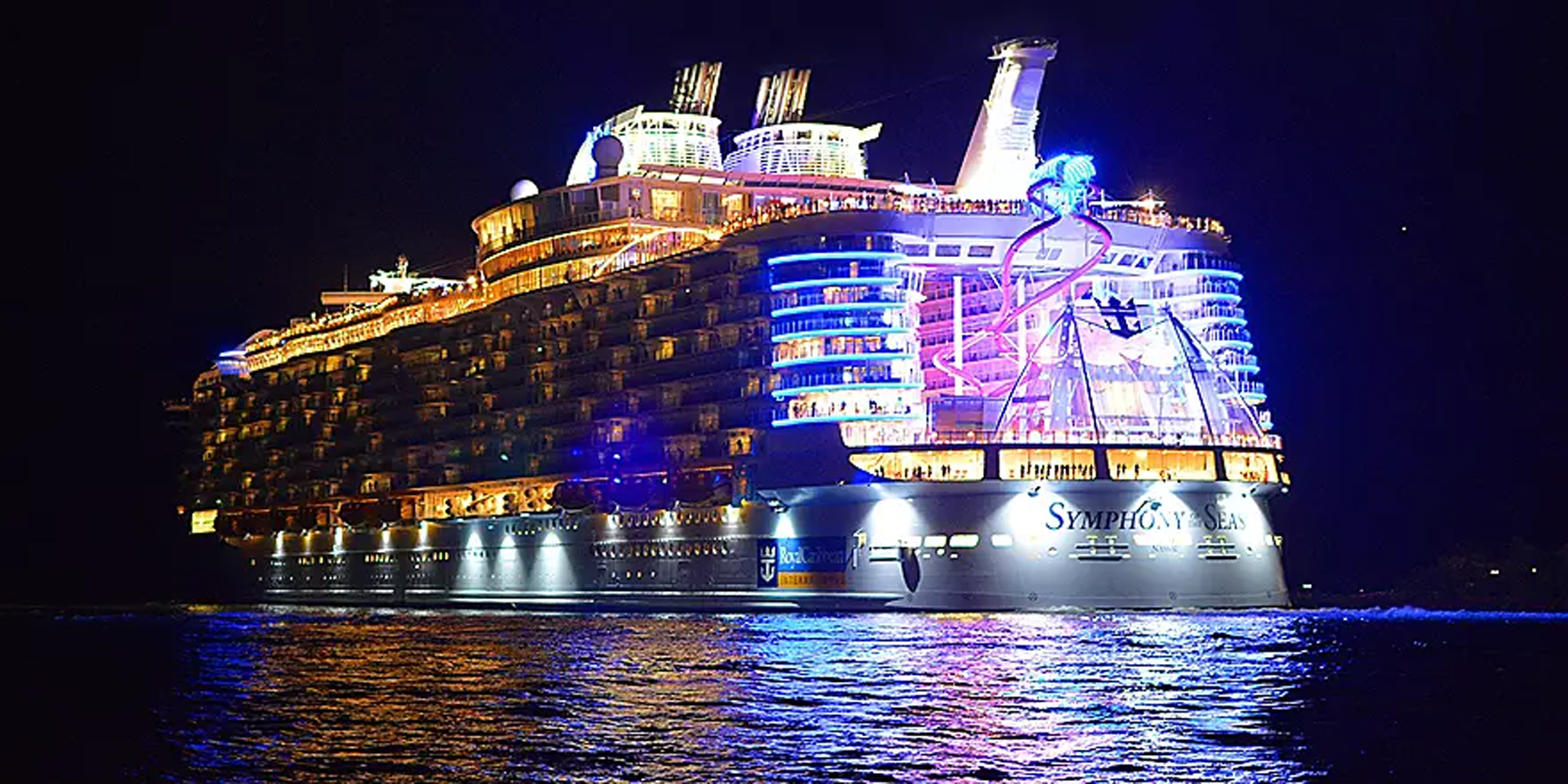 Symphony of the Seas Illuminated at Night A magnificent cruise ship brilliantly lit up at night on dark ocean waters, displaying spectacular
