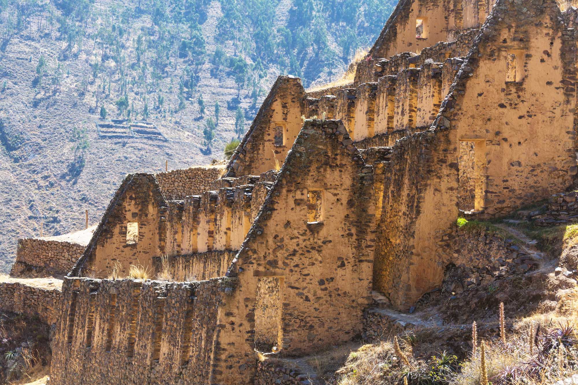 Weathered stone structures of Inca ruins nestled in a mountainous landscape near Cusco, Peru