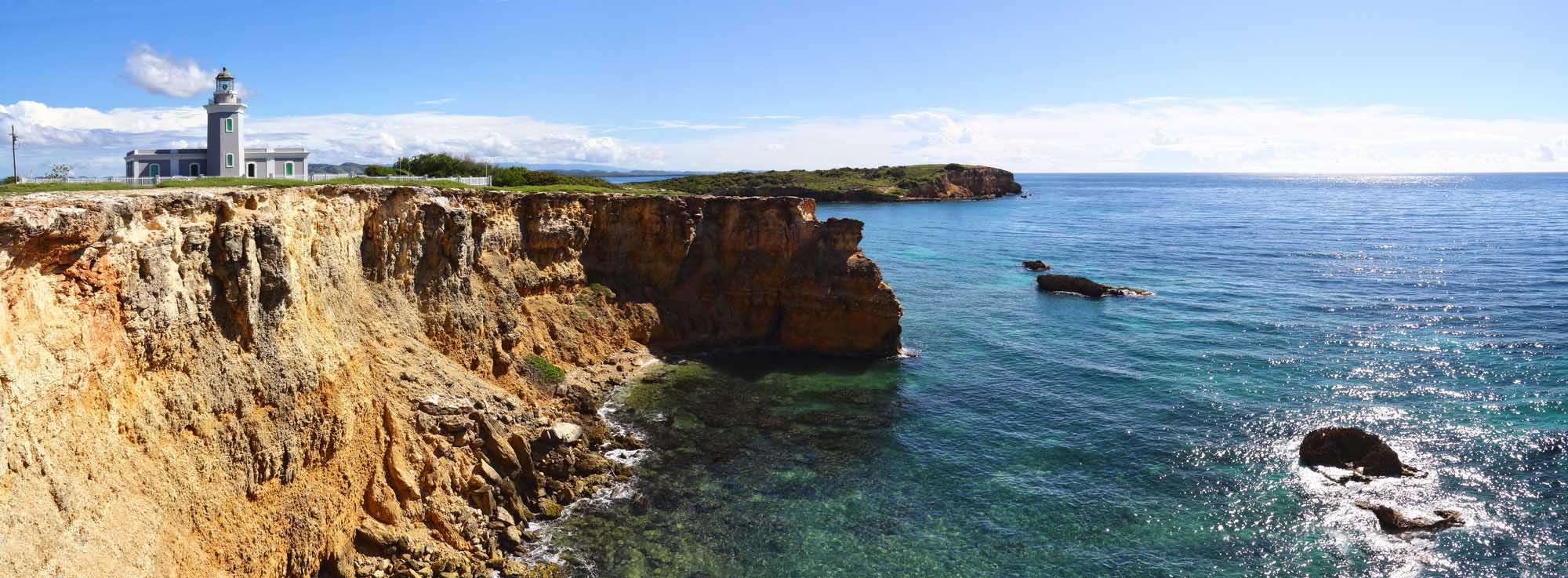 Cabo Rojo Lighthouse on Dramatic Cliffside A picturesque lighthouse stands atop a dramatic cliff overlooking the turquoise Caribbean Sea
