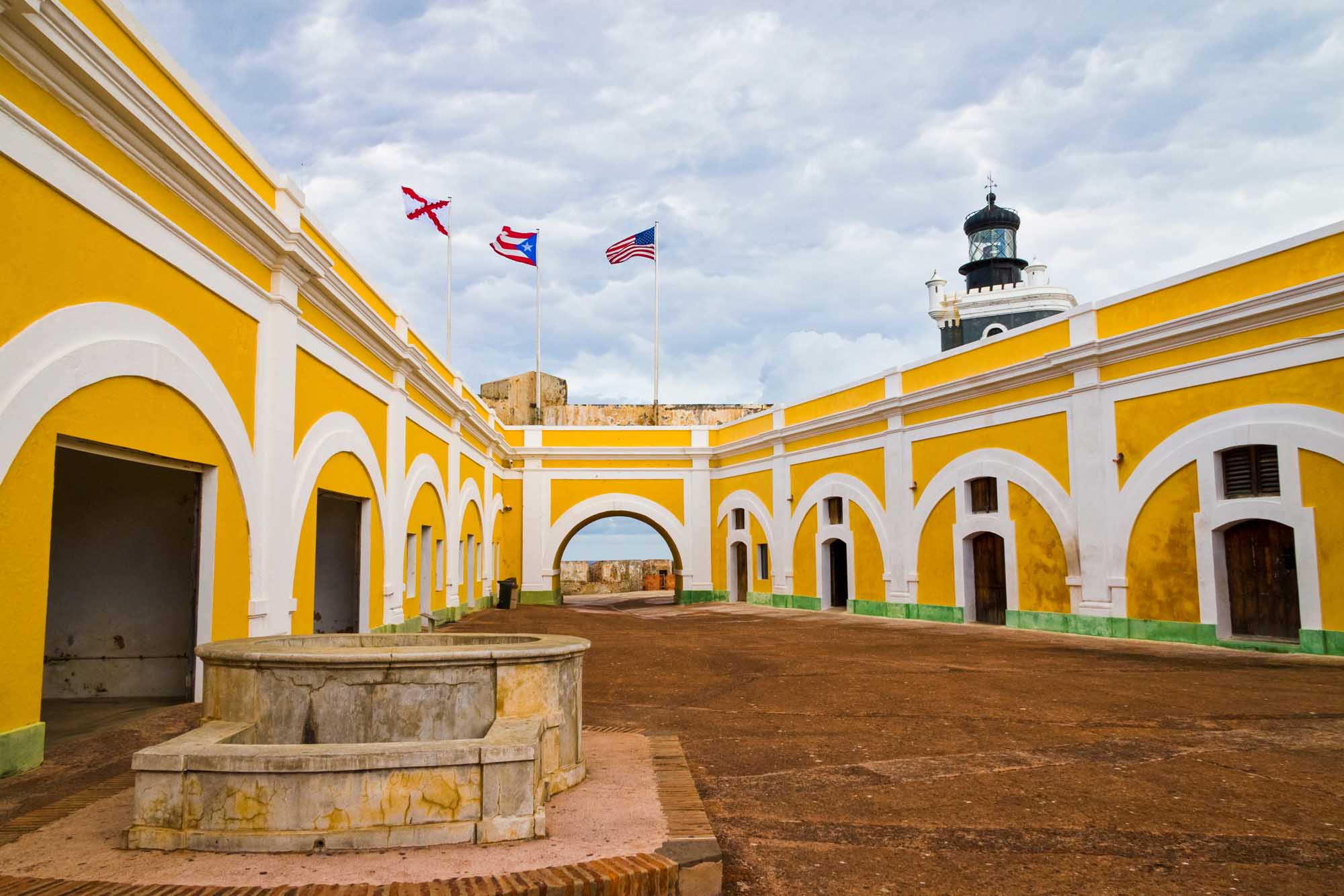 A striking yellow and white colonial fortress courtyard featuring iconic arched galleries