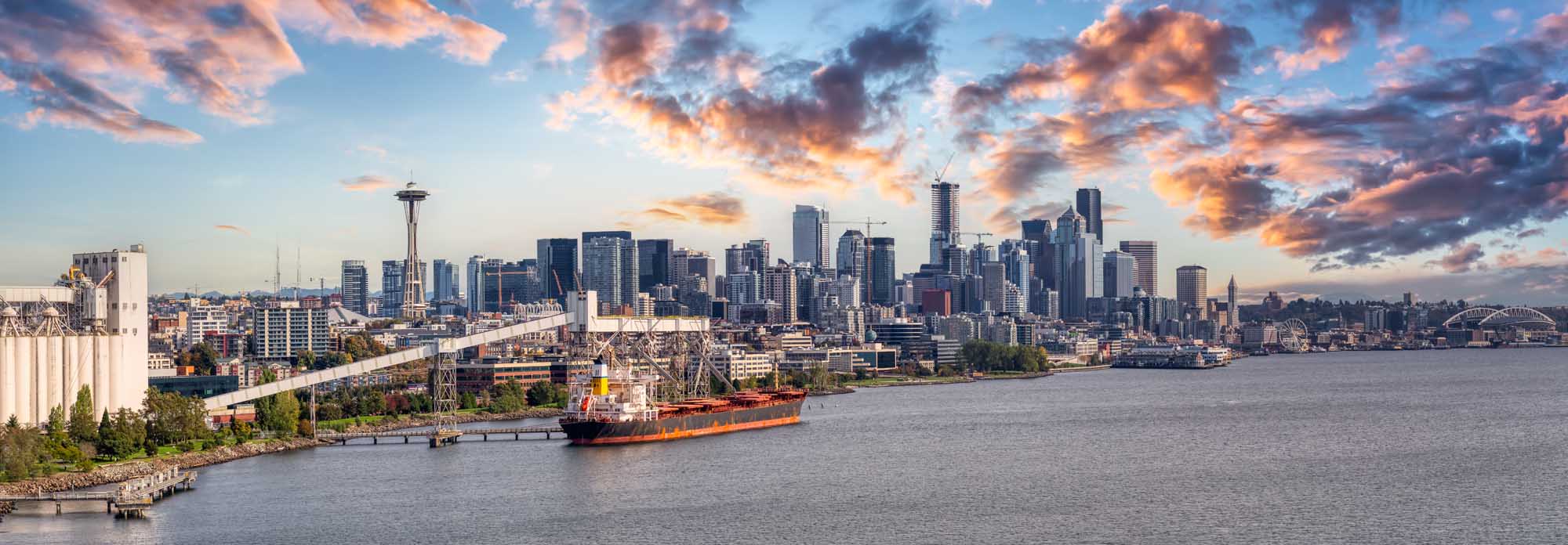 Seattle Skyline at Sunrise with Cargo Ship An aerial panoramic view of downtown Seattle, Washington, featuring the iconic Space Needle