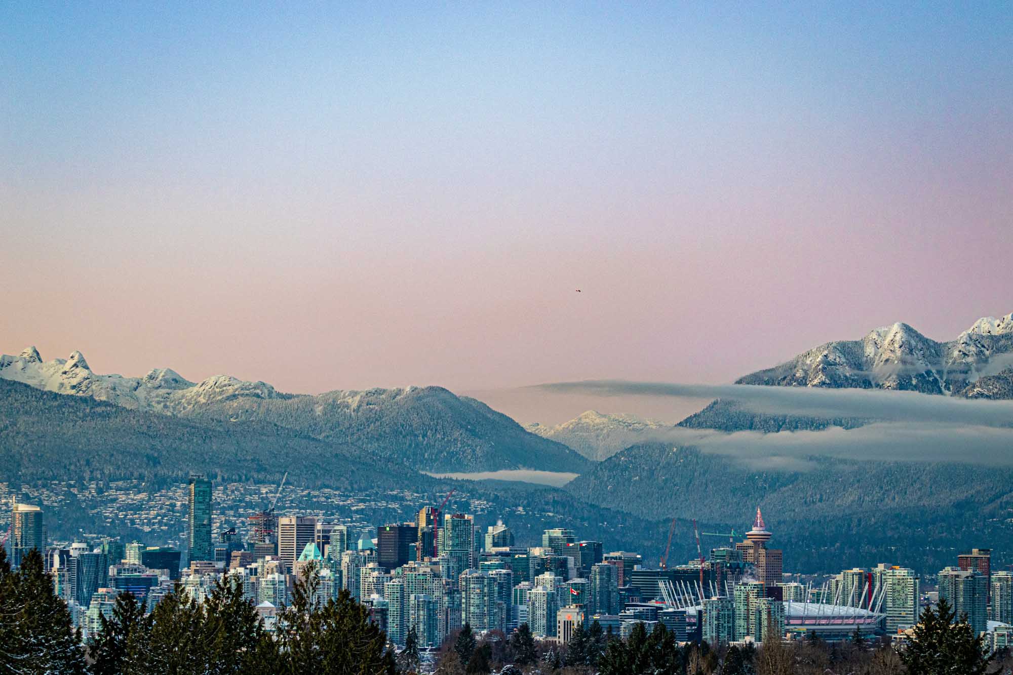 A stunning panoramic view of Vancouver's downtown skyline framed by snow-covered North Shore