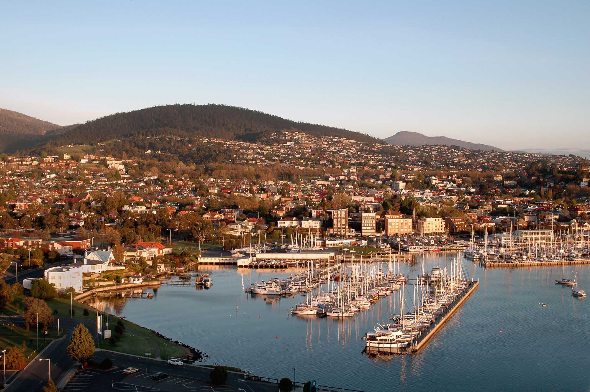 A scenic aerial view of a coastal city with a well-organized marina filled with sailboats in