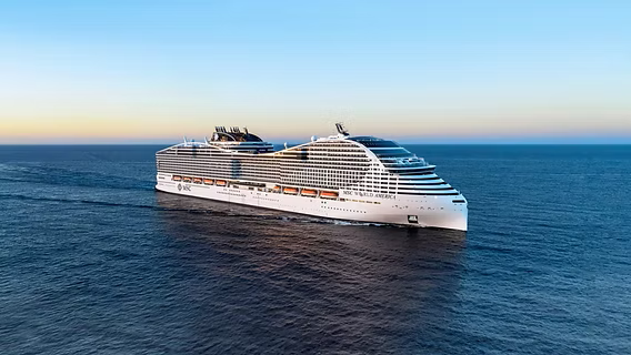 MSC World Europa cruise ship anchored in a Mediterranean port with colorful waterfront town