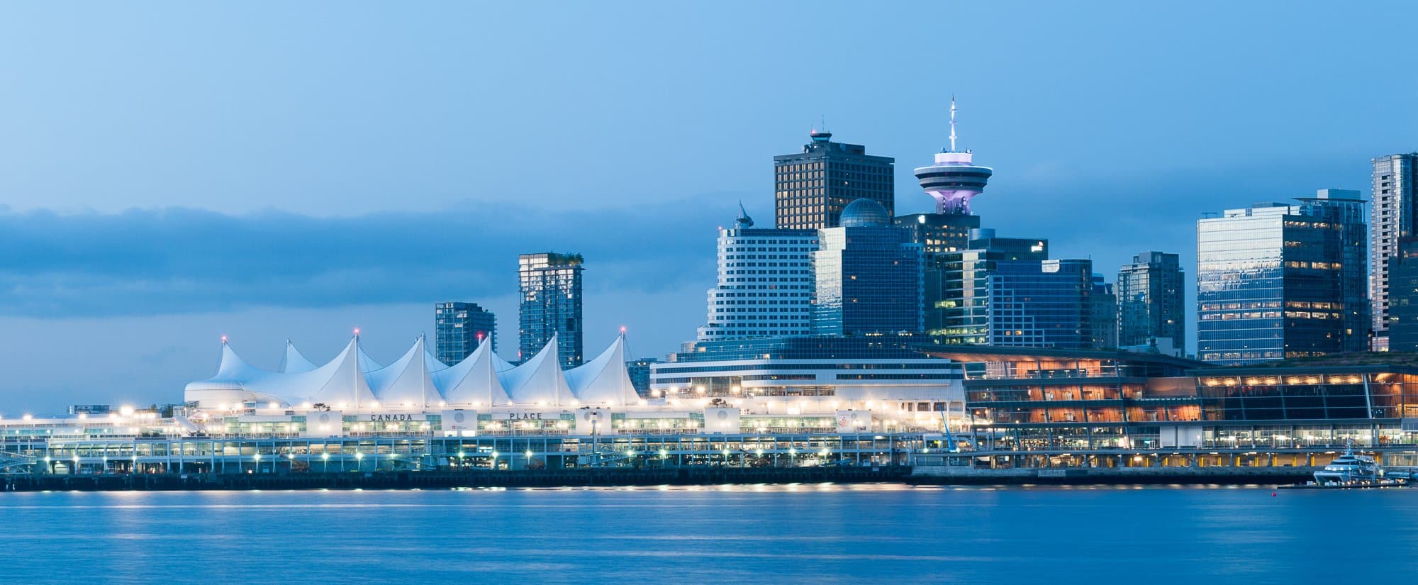 A striking twilight view of Vancouver's downtown skyline featuring the iconic white tent-roofed