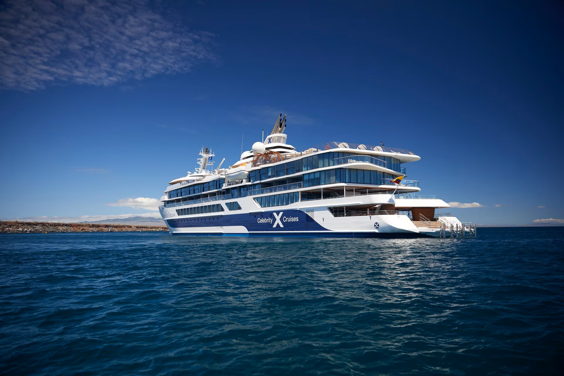 celebrity-flora-galapagos Celebrity Solstice cruising through crystal-clear tropical waters near a mountainous island coastline